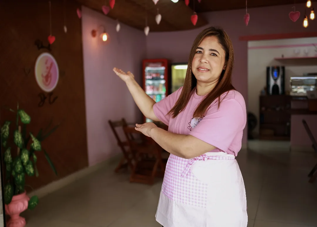 Maraiza, de camiseta e avental cor-de-rosa, mostrando o salão da Pedacinho do Céu